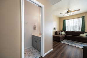 Ensuite bathroom featuring baseboards, connected bathroom, ceiling fan, wood finished floors, and vanity