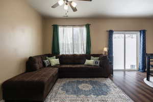 Living room with dark wood-style flooring, a healthy amount of sunlight, ceiling fan, and visible vents