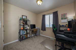 Office space with baseboards, visible vents, and light colored carpet