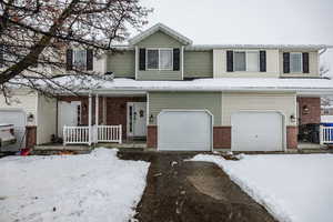 View of front of house with a porch, brick siding, and an attached garage