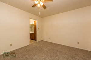 Unfurnished room featuring light carpet, ceiling fan, a textured ceiling, and baseboards