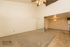 Empty room with stairway, a high ceiling, a ceiling fan, baseboards, and tile patterned floors