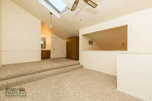 Spare room with visible vents, ceiling fan, vaulted ceiling, a textured ceiling, and carpet flooring