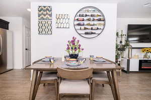 Dining space with baseboards, wood finished floors, and a glass covered fireplace