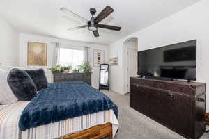 Primary Bedroom featuring a ceiling fan, arched walkways, light carpet, and baseboards