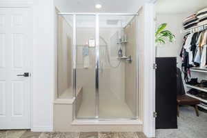 Primary bathroom with a spacious closet and a shower stall