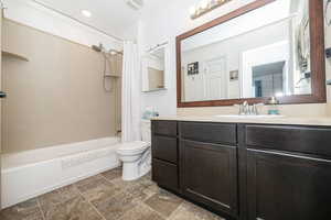 Full bathroom with toilet, shower / bath combo, visible vents, and vanity