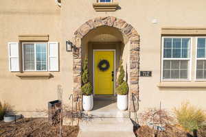 Doorway to property featuring stone siding and stucco siding