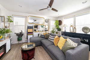 Living room featuring baseboards, light wood finished floors, a ceiling fan, and recessed lighting