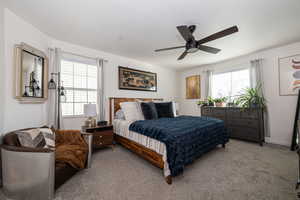 Primary Bedroom with ceiling fan and light colored carpet