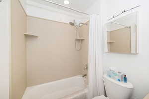 Bathroom with toilet and shower / bath combo with shower curtain