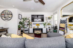 Living area with a textured ceiling, ceiling fan, dark wood-style flooring, and visible vents