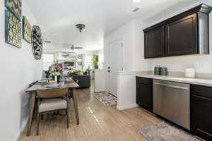 Kitchen featuring light countertops, light wood-style flooring, open floor plan, dishwasher, and baseboards