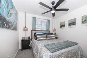 Carpeted bedroom featuring ceiling fan and baseboards