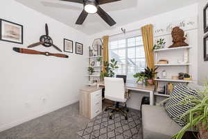 Carpeted office with a ceiling fan and baseboards