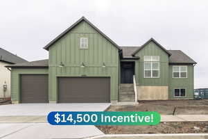 View of front of home with board and batten siding, concrete driveway, and roof with shingles