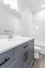 Bathroom with toilet, shower / bathing tub combination, wood finished floors, and vanity