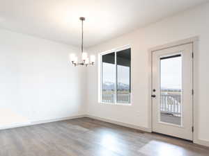 Interior space featuring baseboards, a healthy amount of sunlight, an inviting chandelier, and wood finished floors