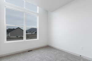 Carpeted spare room with visible vents and baseboards