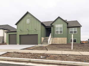 View of front of home featuring board and batten siding, roof with shingles, driveway, and an attached garage