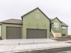 View of front of home featuring roof with shingles, board and batten siding, and concrete driveway