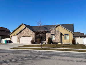 View of front of house with concrete driveway, stone siding, an attached garage, fence, and stucco siding