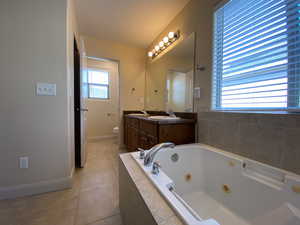 Bathroom featuring double vanity, toilet, a sink, a tub with jets, and tile patterned floors