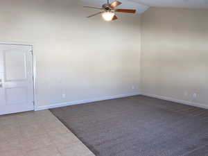 Unfurnished room featuring lofted ceiling, ceiling fan, baseboards, and light tile patterned flooring