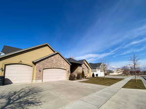 View of front of home with an attached garage, concrete driveway, stone siding, a residential view, and stucco siding