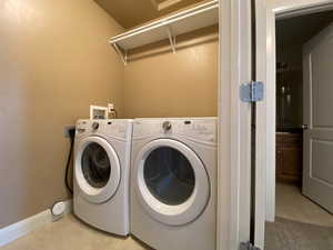 Clothes washing area with laundry area, baseboards, separate washer and dryer, and light tile patterned flooring