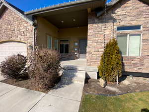 Doorway to property featuring stone siding, an attached garage, and stucco siding