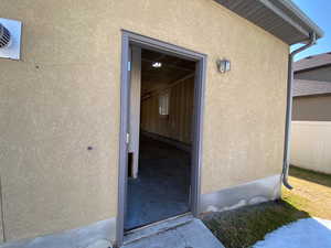 Doorway to property featuring fence and stucco siding