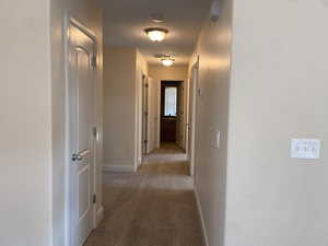 Hallway featuring light colored carpet, visible vents, and baseboards