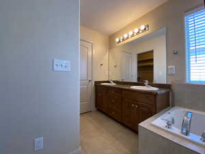 Full bath featuring double vanity, a closet, tile patterned flooring, and a sink