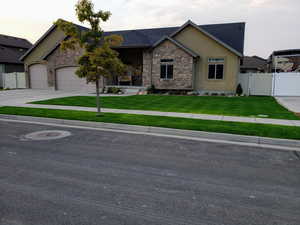 View of front of home featuring driveway, an attached garage, fence, and a yard