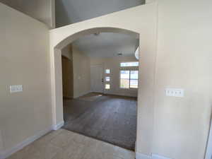 Entrance foyer with arched walkways, light colored carpet, baseboards, and light tile patterned flooring