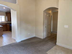 Unfurnished room with light tile patterned floors, arched walkways, and light colored carpet