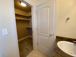 Bathroom with tile patterned flooring, a walk in closet, and vanity