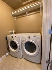 Laundry area with light tile patterned floors, laundry area, washing machine and clothes dryer, and baseboards