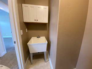 Washroom featuring light carpet, a textured wall, light tile patterned floors, and baseboards