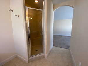 Bathroom featuring a stall shower, tile patterned floors, and baseboards