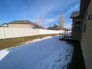 Yard layered in snow with a fenced backyard