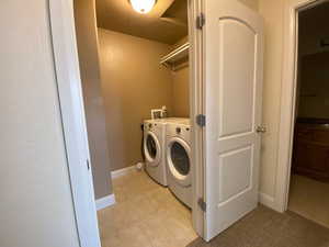 Laundry area with light tile patterned floors, laundry area, baseboards, and washer and dryer