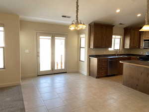 Kitchen with appliances with stainless steel finishes, dark countertops, decorative light fixtures, and a sink