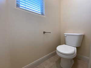 Bathroom featuring toilet, baseboards, and tile patterned floors