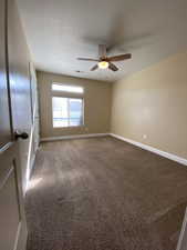 Carpeted empty room with a ceiling fan, visible vents, and baseboards