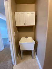 Laundry area featuring light carpet, light tile patterned flooring, and baseboards