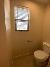 Bathroom with toilet, tile patterned flooring, and baseboards