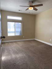 Carpeted spare room featuring a ceiling fan, visible vents, and baseboards