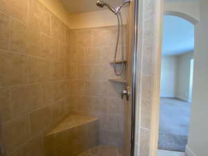 Bathroom with a tile shower and baseboards